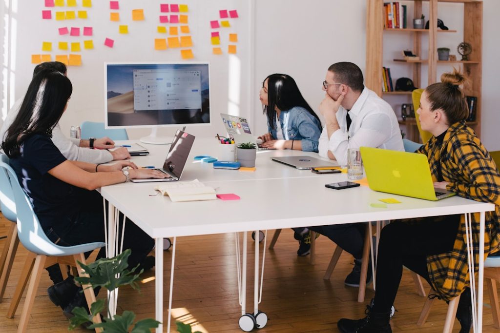 A team sitting at a white table with laptops looking at a computer screen about account planning.
